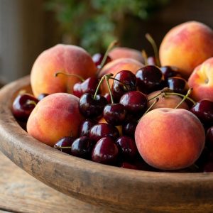 Fresh Palisade peaches and dark sweet cherries in a wooden bowl